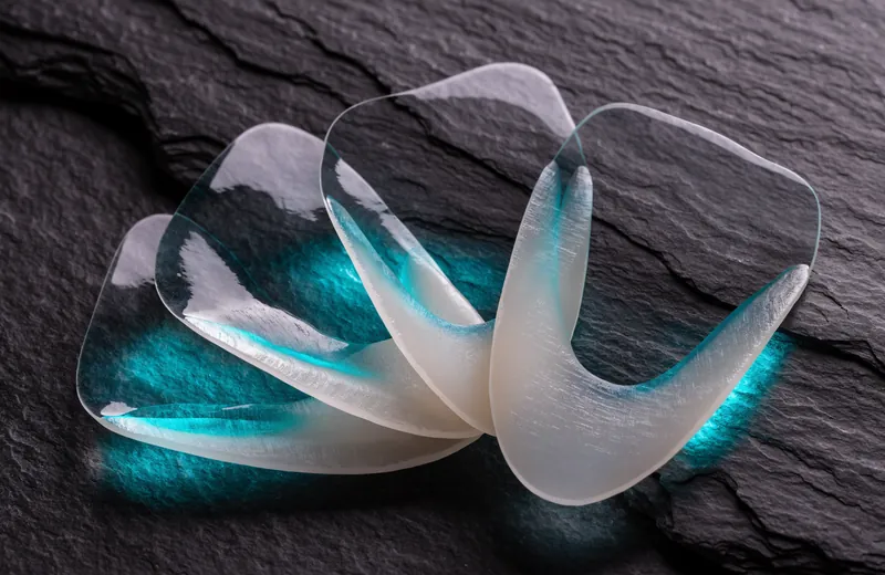 Ultra-thin translucent ceramic veneer shells fanned out on dark slate