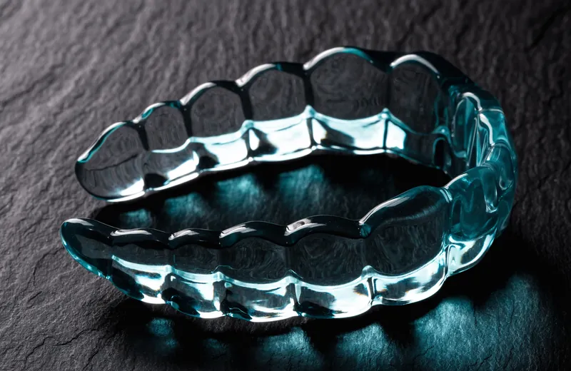 Transparent custom dental night guard on a dark slate surface